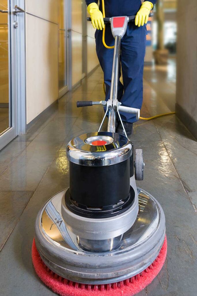 Person using a floor polishing machine in a hallway.